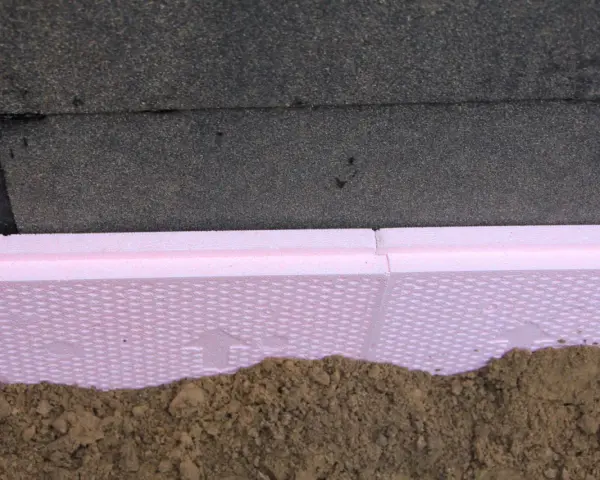 Różowa folia kubełkowa na styropianie chroni fundament przed wilgocią i uszkodzeniami.