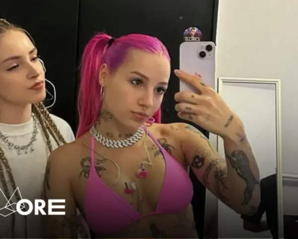 Dwie dziewczyny, jedna z różowymi włosami, druga z warkoczami, pozują do selfie. Jedna z nich, w różowym bikini, ma widoczne tatuaże. W tle logo "Going. MORE".