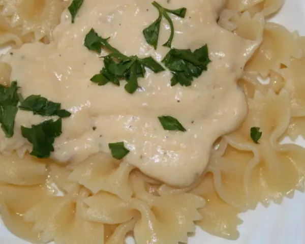 Pyszny sos serowy do makaronu farfalle, udekorowany świeżą natką pietruszki. Idealny na szybki obiad.