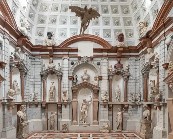 Interno del Palazzo Grimani a Venezia, un tripudio di sculture classiche e busti antichi che adornano nicchie e mensole, creando un'atmosfera di maestosa antichità.