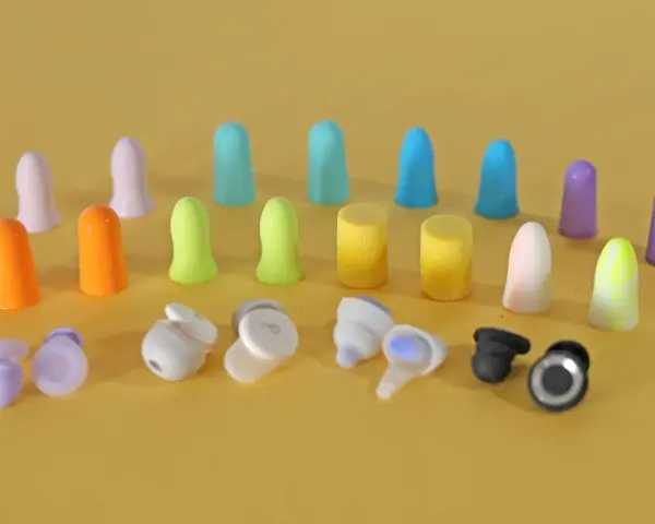 Apprenez comment mettre des bouchons d'oreilles en mousse. Divers bouchons colorés et écouteurs sans fil sont disposés sur fond jaune.