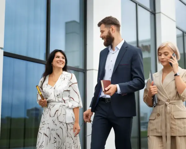 Mujeres con estilo para una conferencia: una con vestido estampado y clutch dorado, otra con traje de lino a rayas y hablando por teléfono.