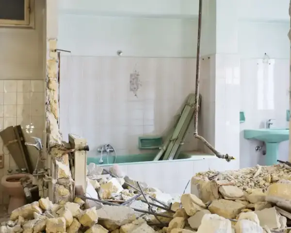 Ruiny łazienki po remoncie. Zniszczone ściany, gruz i wanna. Kara za mieszkanie w nieodebranym domu.