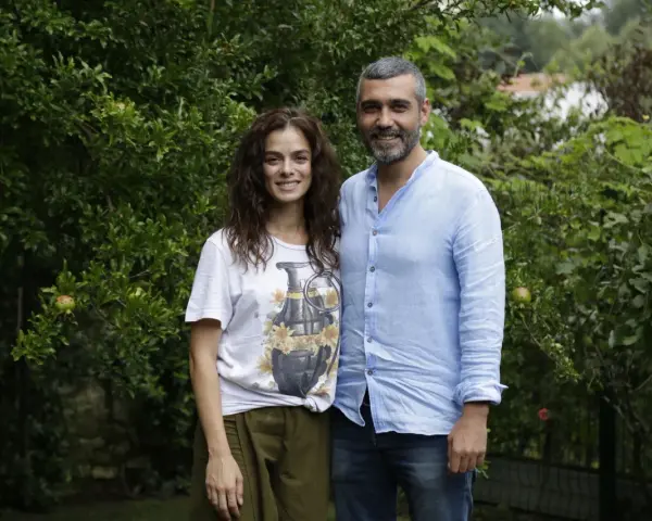 La forza di una donna puntata di oggi: una coppia sorride tra gli alberi. Lei indossa una maglietta con una bomba floreale, lui una camicia azzurra.
