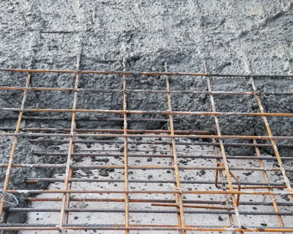 Zbrojenie fundamentów z betonu. Siatka z prętów stalowych pokryta świeżą masą betonową, gotowa do utwardzenia.
