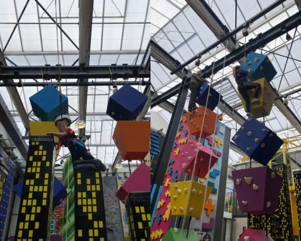 Kinder klettern auf bunte Würfel und Wolkenkratzer in einer Kletterhalle, die an einen Magic Mountain Berlin erinnert.