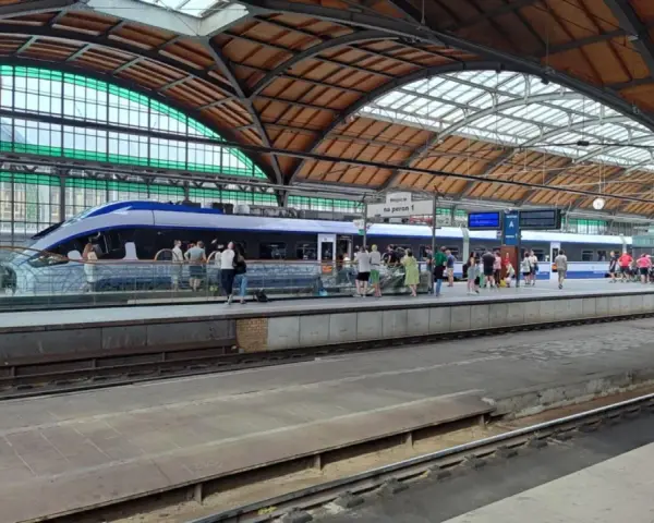 Nowoczesny pociąg kraków wrocław na peronie, pasażerowie czekają na podróż pod zabytkowym zadaszeniem dworca.
