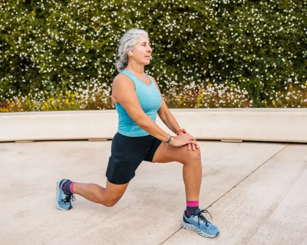 Femme âgée faisant un étirement des jambes, préparation pour un échauffement pieds randonnée.