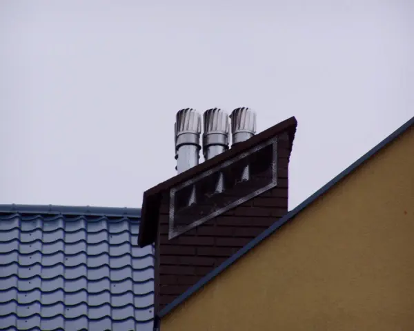 Trzy obrotowe nasady kominowe zamontowane na ceglanym kominie, zapewniające prawidłowy montaż nasady kominowej.