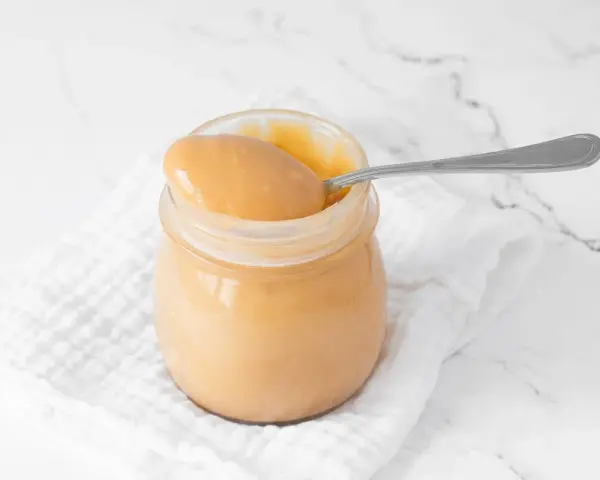 Un tarro de manjar blanco cremoso, listo para ser disfrutado con una cuchara.