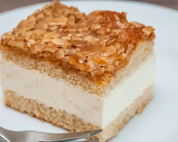 Ein Stück Bienenstich-Kuchen mit cremiger Füllung und karamellisierten Mandeln. Ein leckeres Rezept für den süßen Genuss.