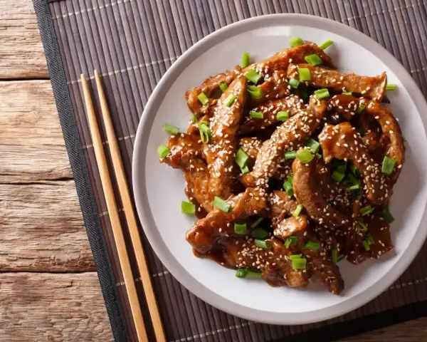 Pyszny kurczak teriyaki z sezamem i szczypiorkiem, gotowy do jedzenia pałeczkami.