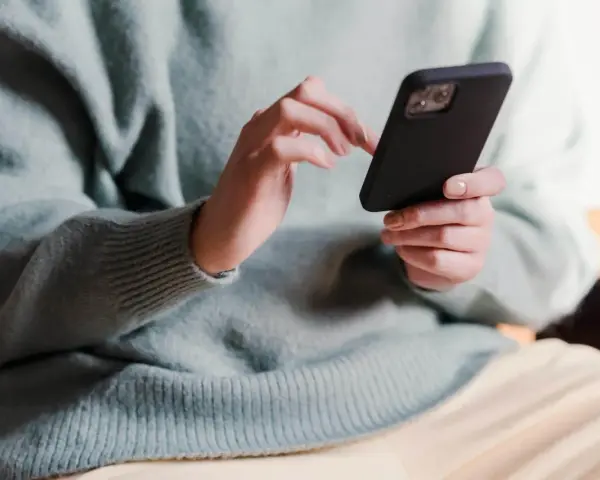Dłonie trzymające telefon, zastanawiające się, co napisać po kłótni.