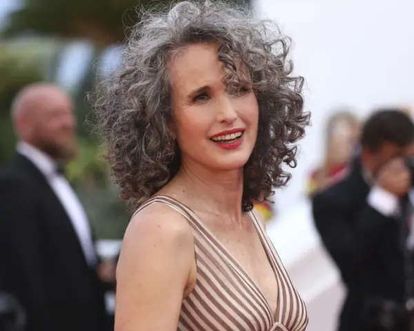 Mujer sonríe con modernos cortes de pelo con canas, luciendo un vestido a rayas.