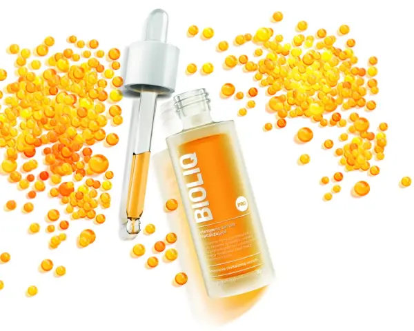 BiolIQ intensywne serum rewitalizujące w buteleczce z pipetą, otoczone kropelkami o pomarańczowym odcieniu.