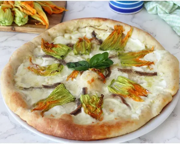 Pizza con fiori di zucca, mozzarella filante e acciughe. Un sapore delicato e profumato, perfetto per l'estate.