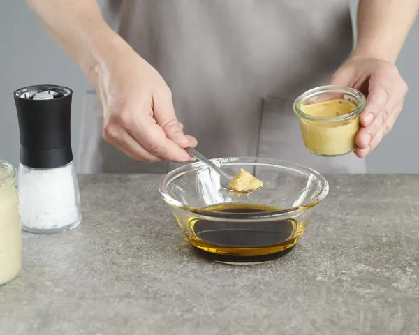 Senf wird zu einer Schüssel mit Öl und Balsamico-Dressing gegeben.