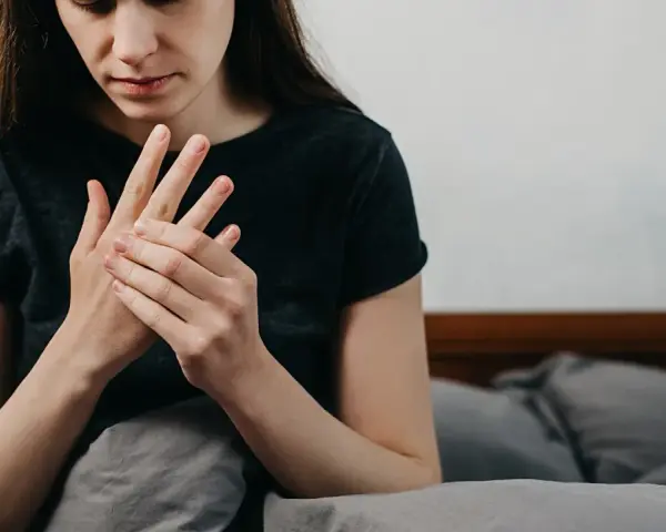 Kobieta masuje dłoń, odczuwając drętwienie rąk w nocy.