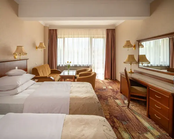 Pokój w hotelu Gołębiowski Wisła: dwa łóżka, kanapa, fotele, biurko i lustro.