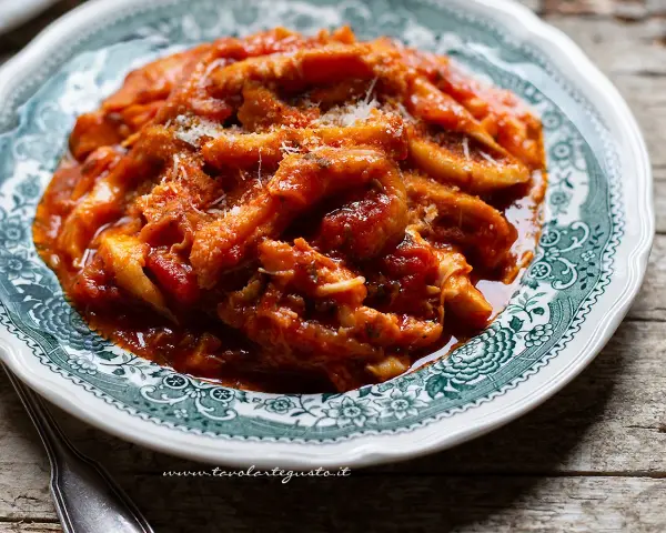 Un piatto fumante di trippa alla romana, ricca e saporita, servita su un piatto decorato.