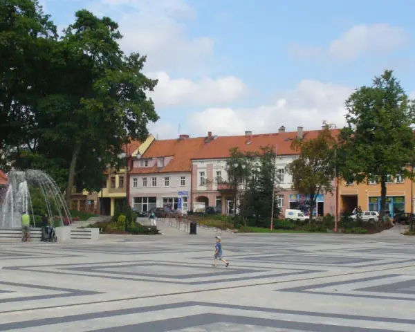 Dziecko biega po placu z fontanną, otoczonym kamienicami. To największy rynek w Polsce, tętniący życiem.