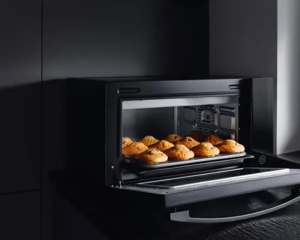 Horno de leña empotrado con bandeja de muffins recién horneados.