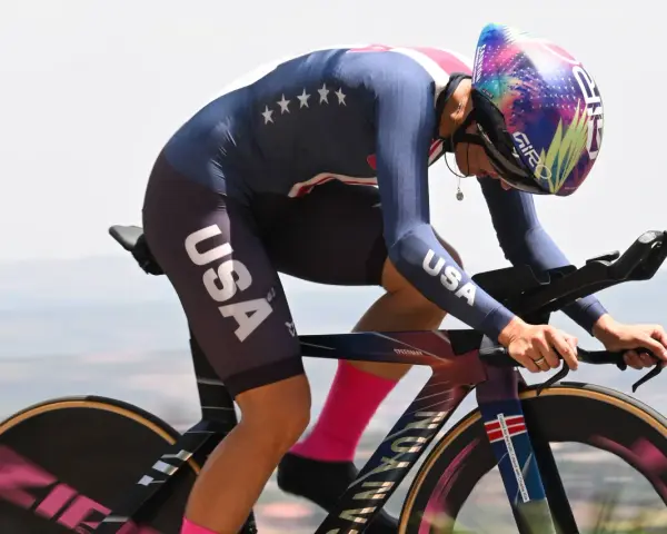 Chloé Dygert, in her USA cycling kit, races against the clock, her focus intense as she powers her bike uphill.