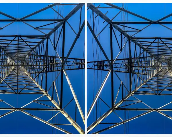 Widok z dołu na kratownicę słupa energetycznego, tworzącą geometryczny wzór na tle błękitnego nieba. To fotografia stereoskopowa.