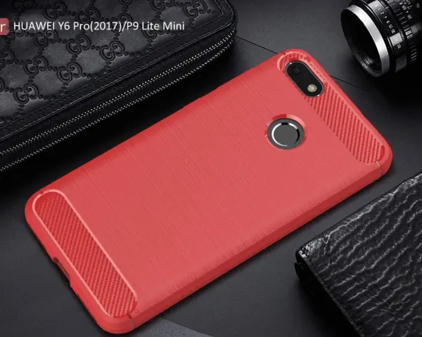 Czerwone etui na telefon Huawei Y6 Pro (2017) z karbonowymi wstawkami, obok czarnego portfela i aparatu.