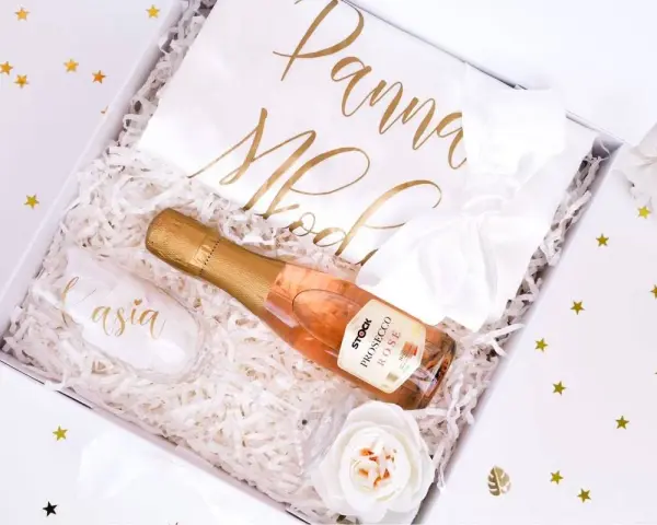 Elegancki prezent na wieczór panieński: kieliszek z imieniem, butelka prosecco i biała szarfa z napisem "Panna Młoda".