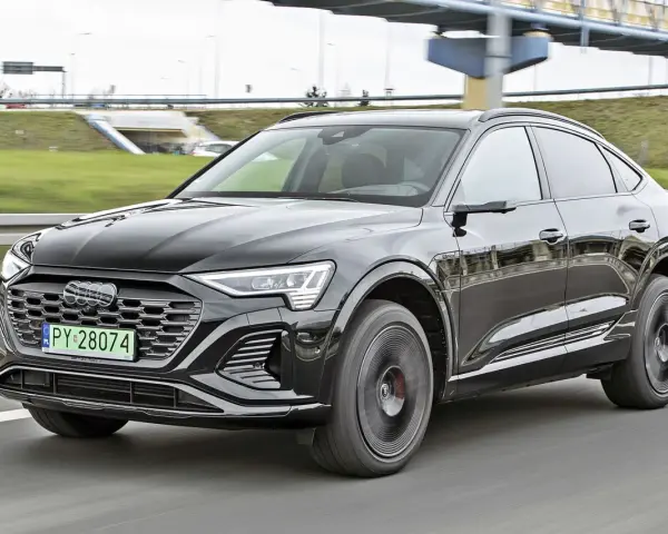 Czarny Audi Q8 e-tron sunie po drodze. Zastanawiasz się nad audi q8 cena? Ten luksusowy SUV coupe robi wrażenie.