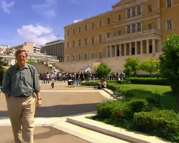 Rick Steves explores Athens, standing before the Hellenic Parliament building with a crowd gathered for the changing of the guard.
