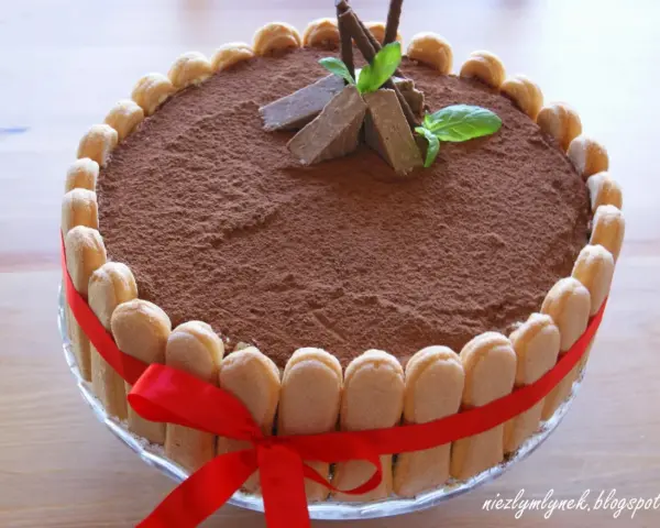 Elegancki tort whisky, udekorowany biszkoptami, kakao i miętą. Czerwona wstążka dodaje mu uroku.