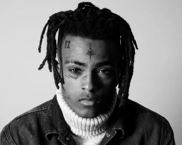Czarno-białe zdjęcie rapera z tatuażami na twarzy, w golfie i kurtce dżinsowej. Wiele osób wspominało go, kiedy umarł xxxtentacion.