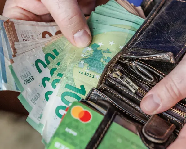 Ręce trzymające euro banknoty i karty płatnicze. Odpowiedź na pytanie: jaka waluta na Litwie? Euro.
