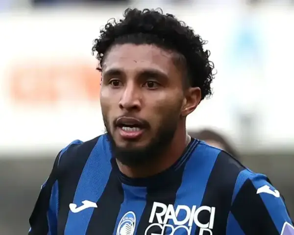 Primer plano de Éderson dos Santos, jugador de fútbol con pelo rizado y barba, vistiendo una camiseta a rayas azules y negras.