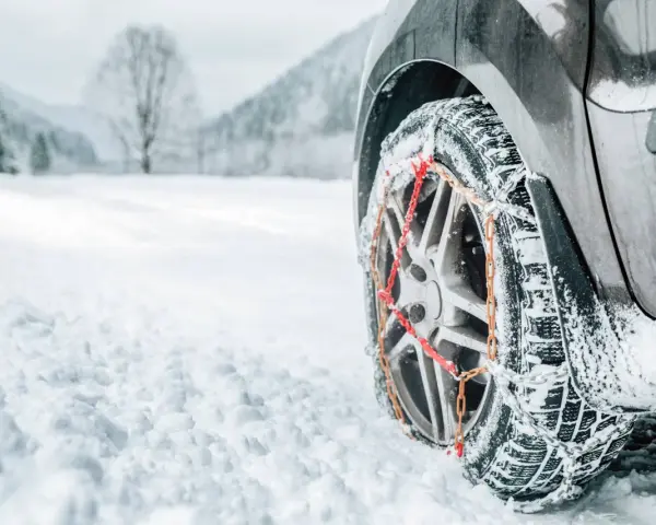 Ruota di un'auto con catene da neve su una strada innevata. Per affrontare la neve, quante catene da neve servono? Di solito due, una per ogni ruota motrice.