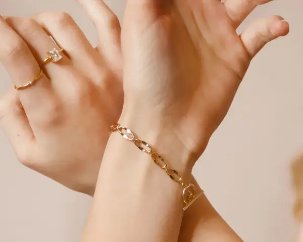 Mani adornate con anelli e un bracciale in metallo che sembra oro, un tocco di eleganza discreta.