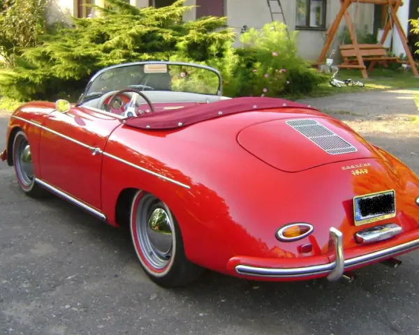 Czerwony kabriolet Porsche 356 z lat 50. stoi na podjeździe, gotowy na letnią przejażdżkę.
