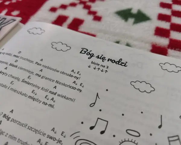 Śpiewnik z kolędami na ukulele. Na stronie tytuł "Bóg się rodzi" i nuty.