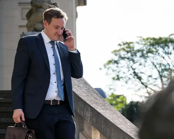 Anwalt am Telefon, der überlegt, wie kann ich mich schnell scheiden lassen. Er trägt einen dunklen Anzug und hält eine Aktentasche.