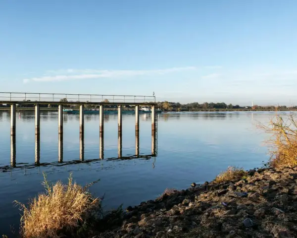 Spokojna tafla wody, pomost i łodzie na rzece tworzą malowniczy krajobraz. To taka kraina z Drohiczynem, gdzie czas płynie wolniej.