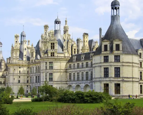 Le château de Chambord, chef-d'œuvre de la Renaissance, se dresse majestueusement sous un ciel bleu. Ses tours et cheminées sculptées rappellent une époque de splendeur.