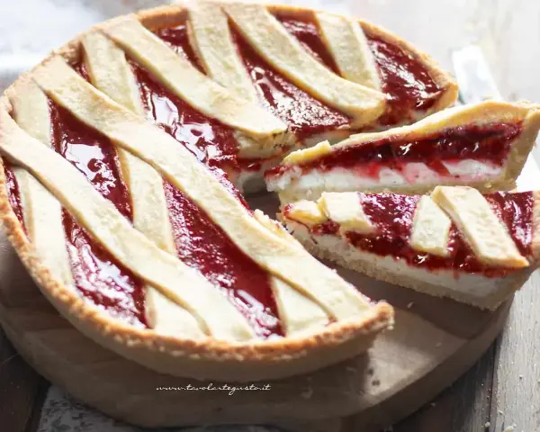 Una deliziosa crostata ricotta e marmellata, con una fetta tagliata per mostrare il ripieno cremoso e la crosta dorata.