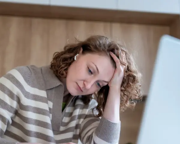 Kobieta z trudnościami z koncentracją opiera głowę na dłoni, patrząc w dół.