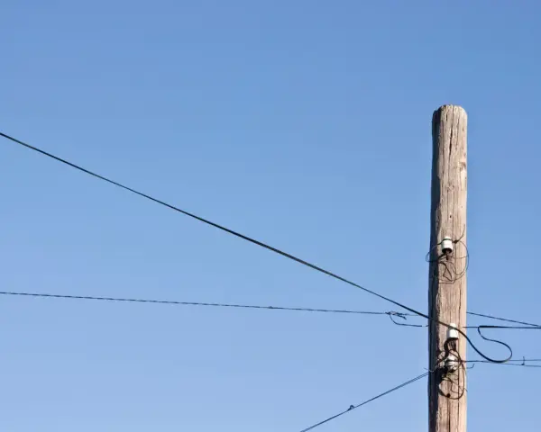 Słup energetyczny z przewodami, symbolizujący zgodę na światłowód nad działką.