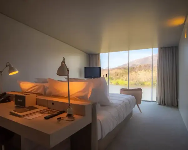 Un angolo studio in camera da letto con vista sul lago. Due lampade illuminano la scrivania con telefono e altoparlante.
