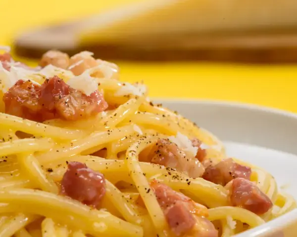 Pyszne spaghetti carbonara z kawałkami boczku i posypką. Szukasz, czym zastąpić parmezan?