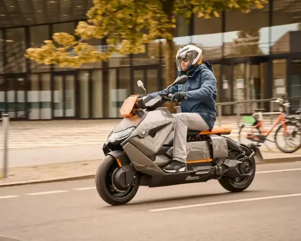 Mężczyzna w kasku jedzie na futurystycznym skuterze BMW CE04 po mieście.