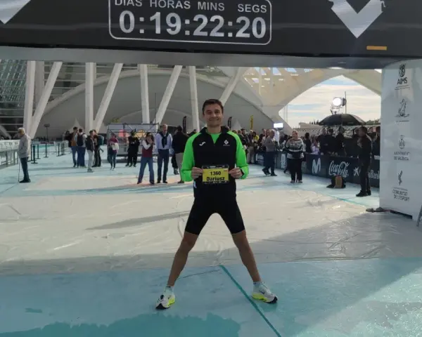 Uśmiechnięty Dariusz z numerem 1360 na piersiach po biegu na maratonie Valencia. Czas na tablicy: 0:19:22:20.